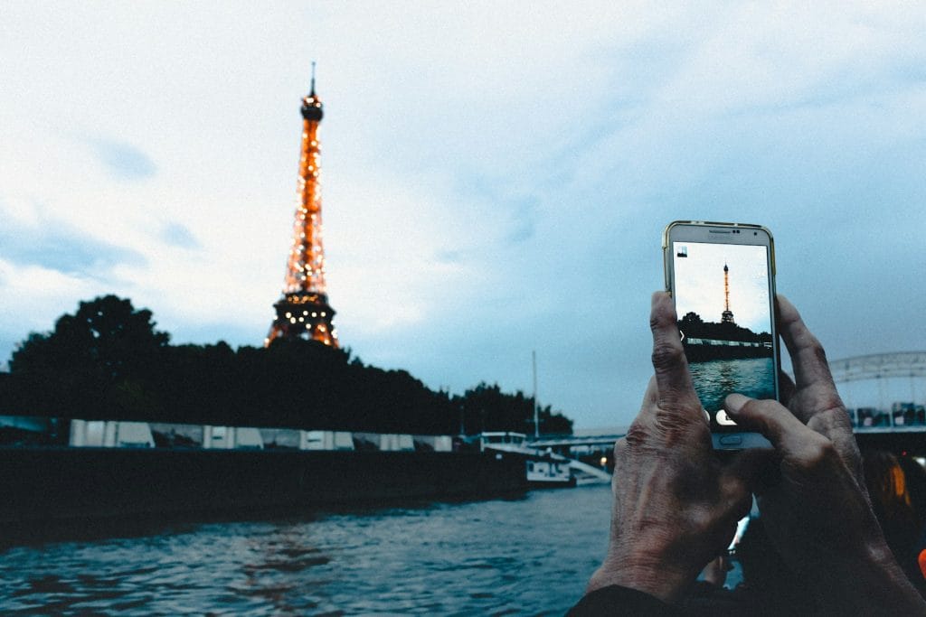 person taking photo of brown tower with smartphone