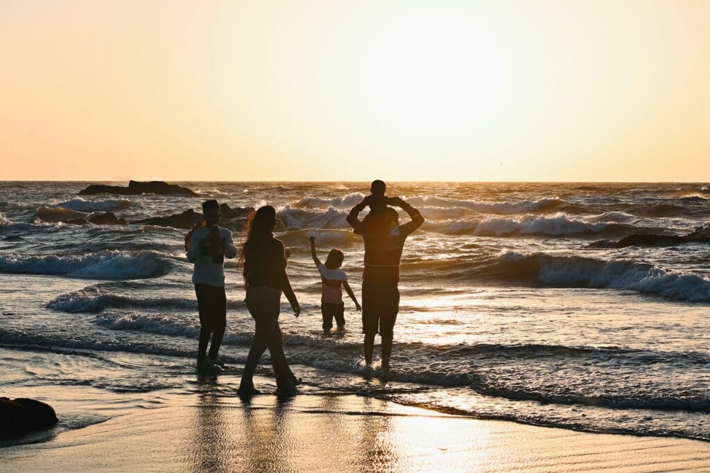 A group of people standing on top of a beach next to the ocean