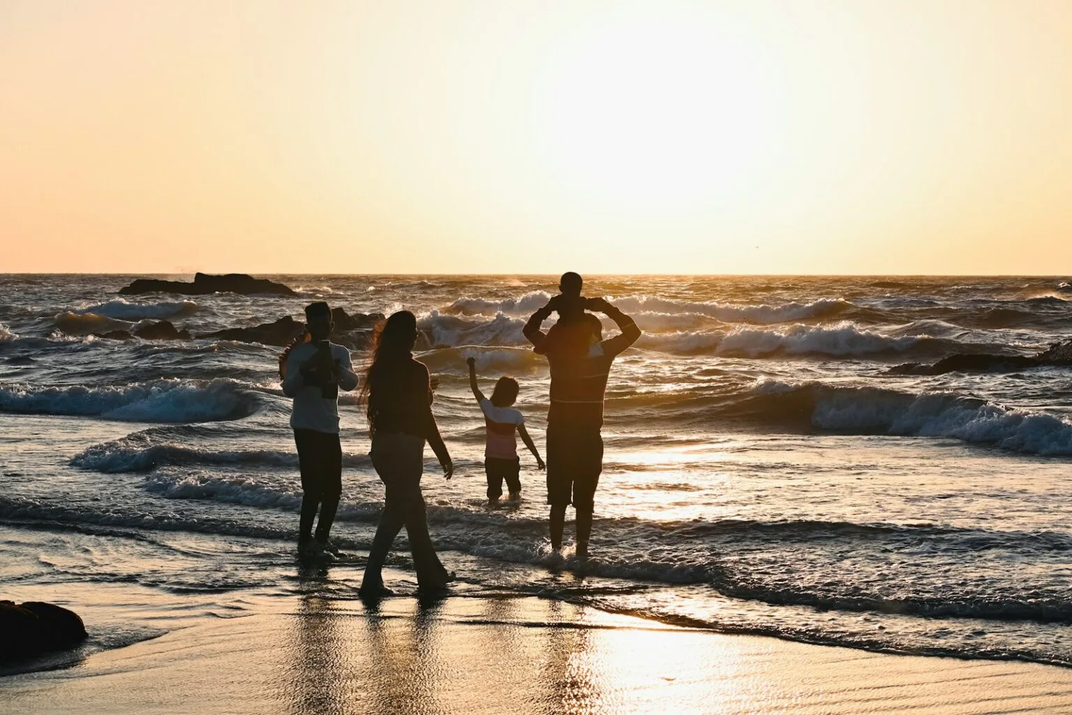 A group of people standing on top of a beach next to the ocean