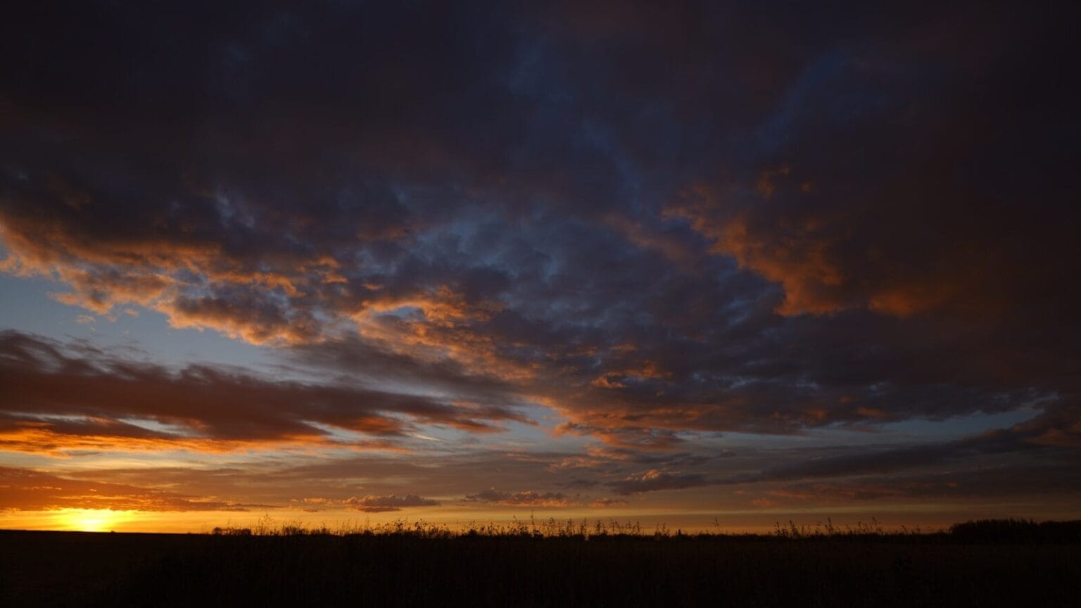 Dramatic sunset sky with colorful clouds over dark horizon